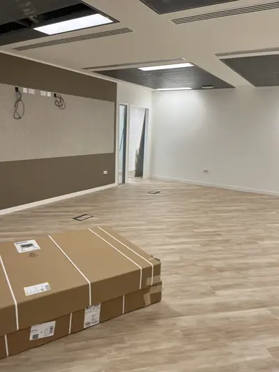 Office room with a brown feature wall and fabric acoustic panel on one side, white walls opposite, and wood-effect flooring.