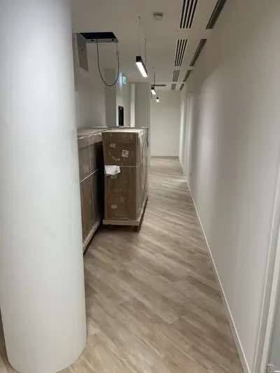 Office corridor with white painted walls and a painted circular column, and wood-effect flooring.
